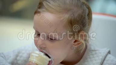 那个金发女孩有趣可爱的小女孩在大购物中心吃冰淇淋和喇叭。 一家人吃冰淇淋